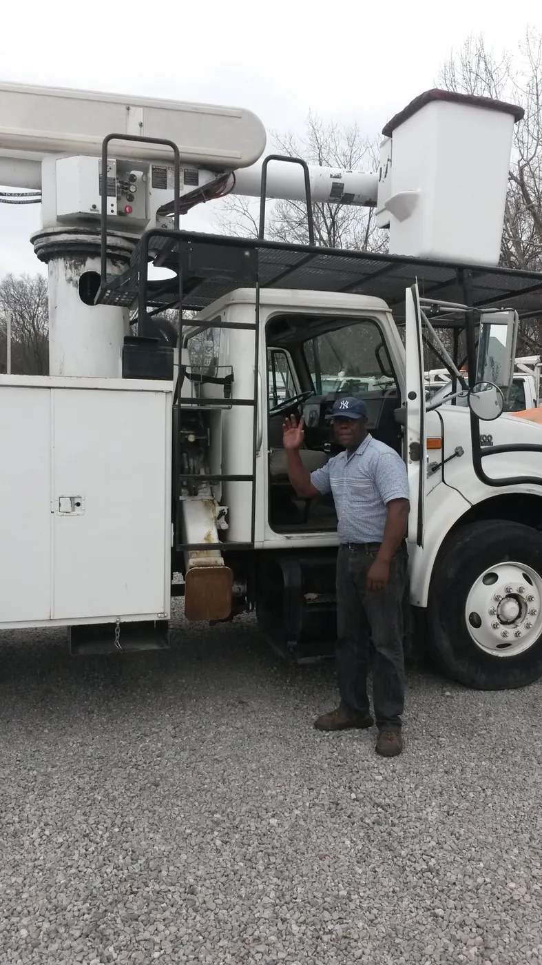 Person standing beside a white bucket truck in an equipment yard